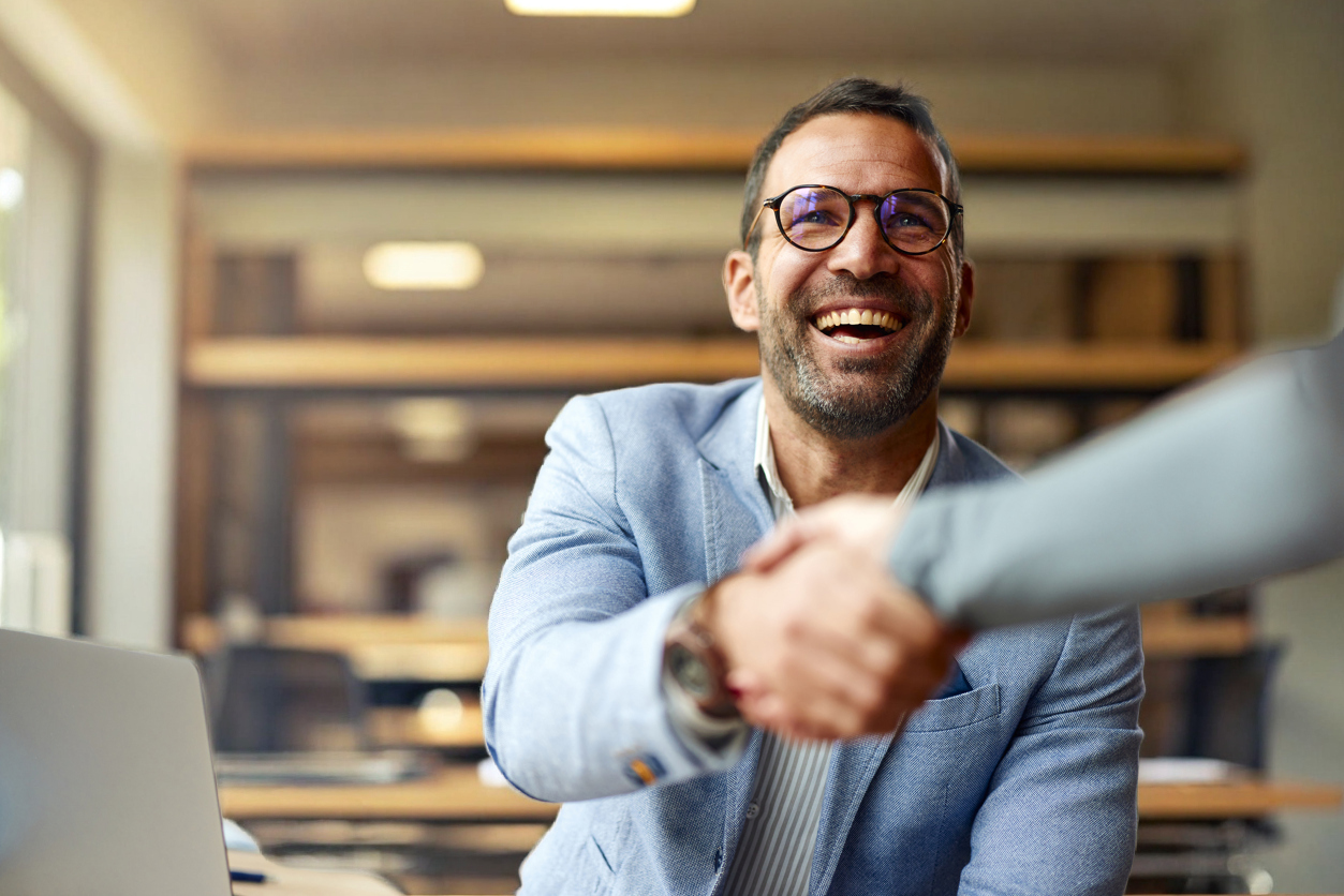 Happy businessman shaking hands with his colleague on a meeting in the office.